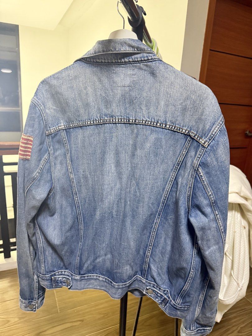 Polo Ralph Lauren Denim Trucker Jacket (Category: Coats, Jackets and Outerwear) located in Mabalacat. Submitted by mykachika (Listing ID 1471087977, Image 3). Description: - Brand: Polo Ralph Lauren - Style: Classic denim jacket with button-up front, chest pockets, and side pockets - Wash: Medium wash - Size: Large (180-100A on tag) - Special Feature: American flag patch on right sleeve with branded metal hardware - Origin: Made in Mexico - Condi