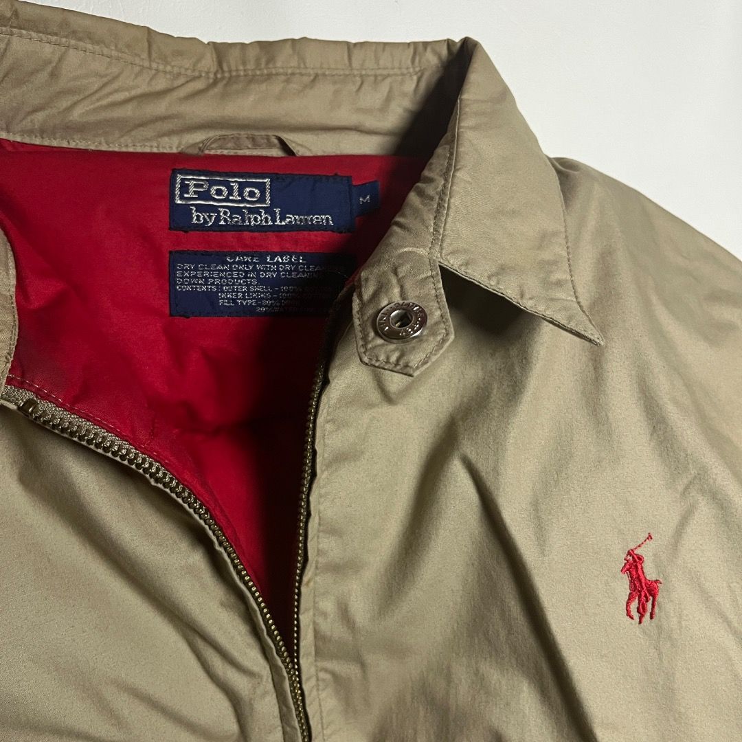 Polo Ralph Lauren Khaki Down Puffer Harrington Jacket (Category: Coats, Jackets and Outerwear) located in Caloocan City. Submitted by achilles_grails (Listing ID 1471052396, Image 3). Description: Polo by Ralph Lauren down jacket in khaki. Red quilted inner lining. Outer shell and inner lining are 100 percent cotton. Fill type is 80 percent down and 20 percent waterfowl feather. Dry clean only. Size M tag on the collar. Classic embroidered red lo