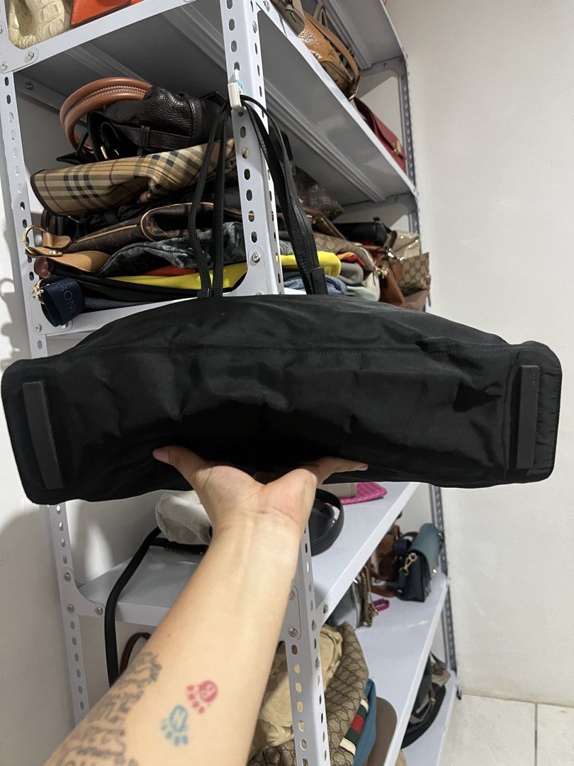 Prada Black Nylon Tote Bag with Leather Straps (Category: Luxury Bags & Wallets) located in Muntinlupa City. Submitted by armendaber03743 (Listing ID 1471089256, Image 3). Description: - Prada black nylon tote bag - Double leather handles with sleek silver-tone hardware - Classic front pocket and iconic enameled triangle logo badge - Structured base with protective metal feet - Spacious interior ideal for daily essentials - Clean fabric with mini