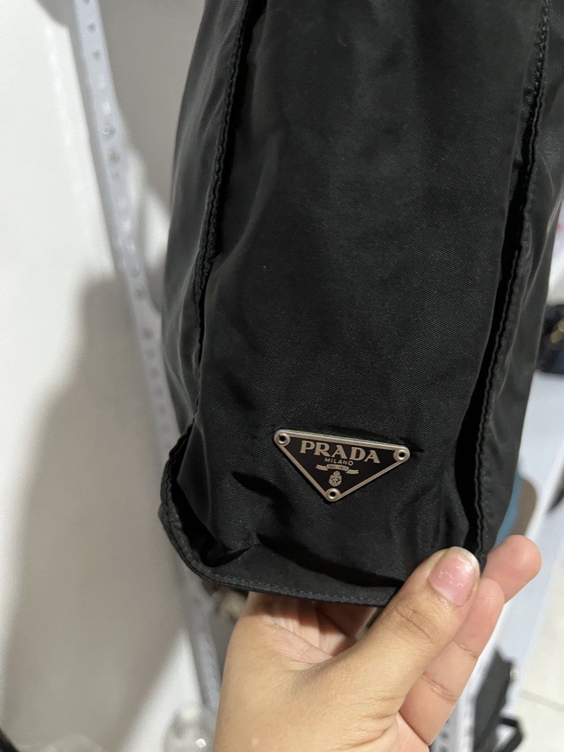 Prada Black Nylon Tote Bag with Leather Straps (Category: Luxury Bags & Wallets) located in Muntinlupa City. Submitted by armendaber03743 (Listing ID 1471089256, Image 2). Description: - Prada black nylon tote bag - Double leather handles with sleek silver-tone hardware - Classic front pocket and iconic enameled triangle logo badge - Structured base with protective metal feet - Spacious interior ideal for daily essentials - Clean fabric with mini