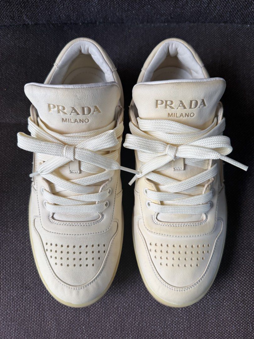 Prada Milano Leather Sneakers Cream White (Category: Sneakers & Footwear) located in Iloilo. Submitted by darvoza (Listing ID 1470965440, Image 1). Description: Prada leather sneakers in cream white colourway. Iconic enameled metal triangle logo on the sides. Perforated toe box and thick rubber soles. Classic low-top silhouette with wide tonal laces. Debossed Prada lettering on the tongue, heel, and side midsole. Made in Italy, model code 2EE364.