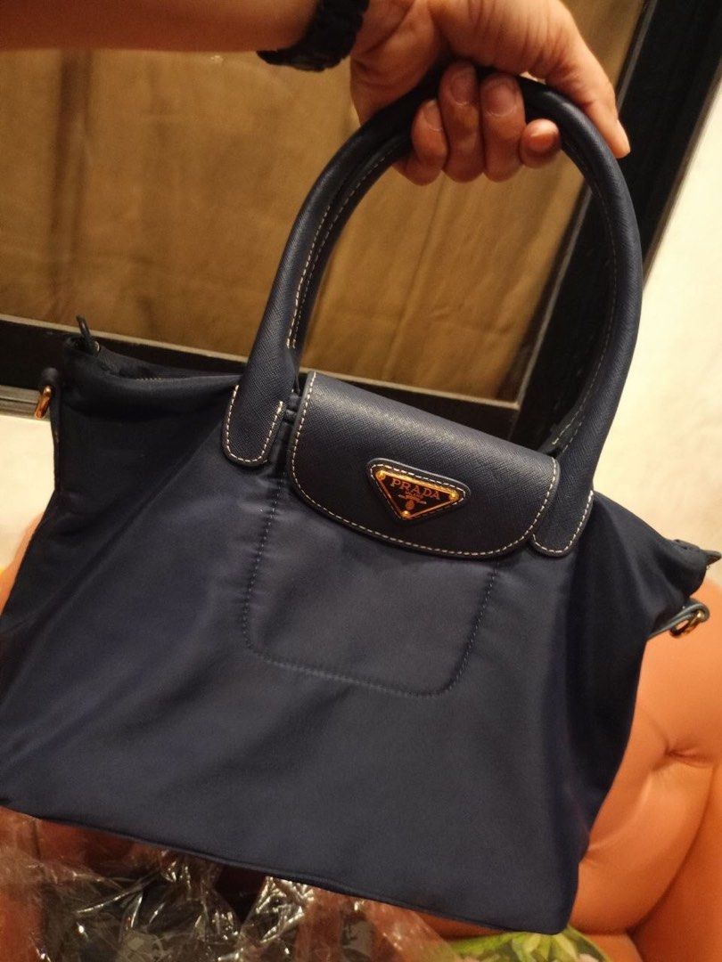 Prada Nylon Flap Top Handle Bag Navy Blue (Category: Luxury Bags & Wallets) located in Quezon City. Submitted by yunajohan24 (Listing ID 1470964041, Image 1). Description: - Authentic Prada navy blue nylon handbag - Premium Saffiano leather trim and gold-tone hardware - Iconic enamel triangle logo on the front flap - Double top handles for comfortable carrying - Secure top zip closure - Signature Prada jacquard lining with interior gold-toned Pra