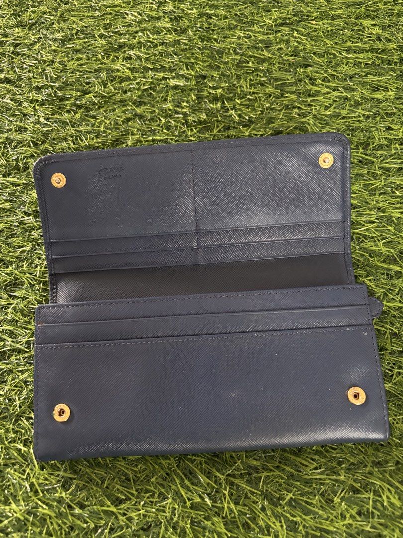 Prada Saffiano Leather Long Wallet Dark Blue (Category: Luxury Bags & Wallets) located in Makati City. Submitted by rare_thrift_stuff (Listing ID 1470963990, Image 2). Description: - Authentic Prada long wallet - Dark blue durable Saffiano leather - Iconic gold-tone metal lettering logo on front - Secure snap button closure - Multiple interior card slots and compartments - Convenient exterior zippered pocket on the back - Interior Prada Milano he