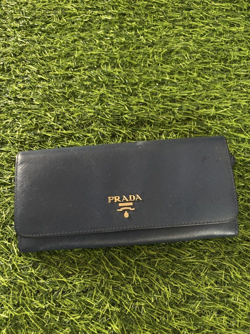 Prada Saffiano Leather Long Wallet Dark Blue (Category: Luxury Bags & Wallets) located in Makati City. Submitted by rare_thrift_stuff (Listing ID 1470963990, Image 1). Description: - Authentic Prada long wallet - Dark blue durable Saffiano leather - Iconic gold-tone metal lettering logo on front - Secure snap button closure - Multiple interior card slots and compartments - Convenient exterior zippered pocket on the back - Interior Prada Milano he