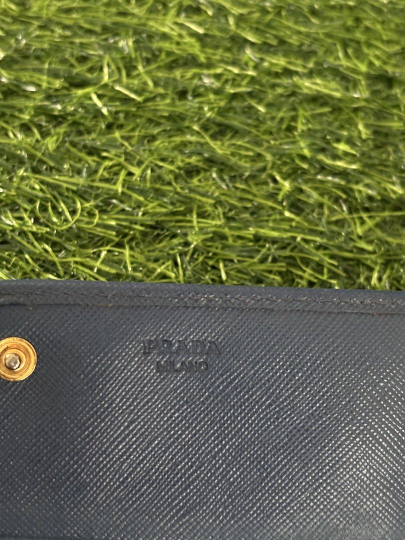 Prada Saffiano Leather Long Wallet Dark Blue (Category: Luxury Bags & Wallets) located in Makati City. Submitted by rare_thrift_stuff (Listing ID 1470963990, Image 3). Description: - Authentic Prada long wallet - Dark blue durable Saffiano leather - Iconic gold-tone metal lettering logo on front - Secure snap button closure - Multiple interior card slots and compartments - Convenient exterior zippered pocket on the back - Interior Prada Milano he