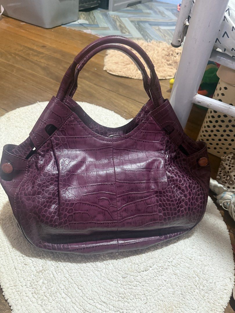 Purple Crocodile Embossed Leather Handbag (Category: Luxury Bags & Wallets) located in Pasig City. Submitted by patrissia1129 (Listing ID 1470977798, Image 1). Description: - Color/Texture: Rich purple with all-over faux crocodile finish - Closure: Secure magnetic snap - Interior: Matching purple fabric lining with a zipped compartment for small items - Capacity: Deep interior that easily fits everyday essentials - Design: Double handles with stu