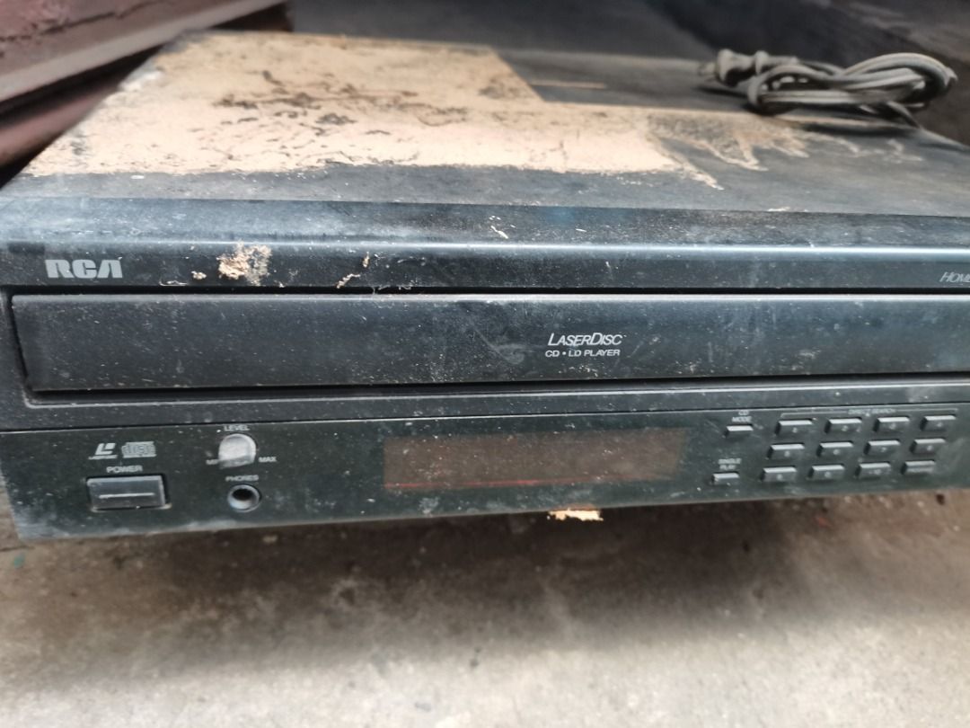 RCA LaserDisc CD Player (Category: Portable Music Players) located in Makati City. Submitted by tentanten (Listing ID 1471066307, Image 1). Description: - Brand/Model: RCA Laserdisc and CD player unit - Color: Classic black with attached power cord - Features: Standard front control buttons, headphone jack, and volume knob - Condition: Dusty from storage, untested power status, requires a thorough cleanup - Perfect project piece for vintage elect