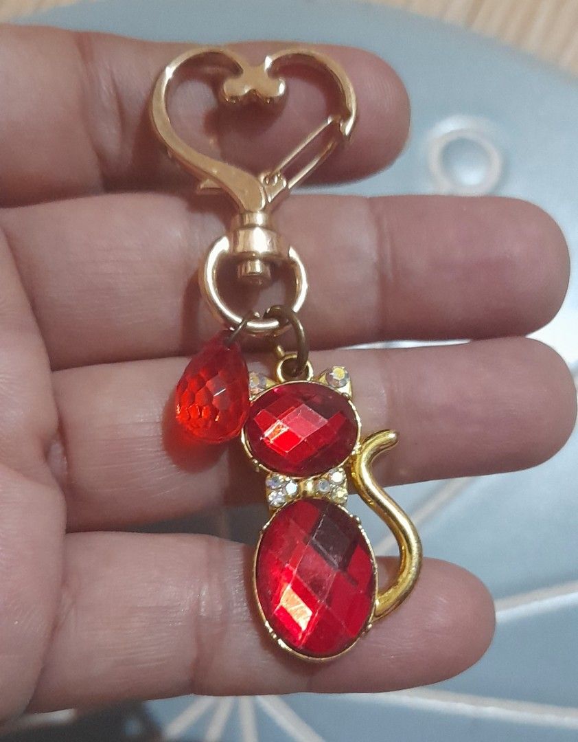 Red Crystal Cat Keychain Gold Hardware Heart Clasp (Category: Charms) located in Bocaue. Submitted by marajapansurplus (Listing ID 1470980516, Image 1). Description: - Adorable gold-tone cat keychain filled with sparkling red faceted crystals - Accentuated with small clear rhinestones around the collar - Features a cute extra dangling red teardrop bead - Equipped with a smooth, reliable heart-shaped clasp - Plain textured gold metal finish on the