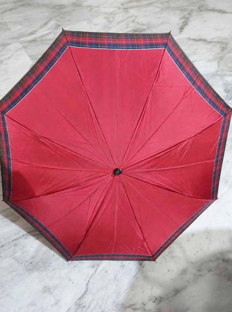 Red Foldable Umbrella with Tartan Plaid Trim (Category: Umbrellas) located in Caloocan City. Submitted by chonadura91470 (Listing ID 1471104909, Image 1). Description: - Color: Deep red with subtle vertical striping and classic tartan plaid trim - Design: Foldable with a dark frame and black handle featuring a convenient wrist strap - Portability: Collapses down neatly into a compact matching sleeve with a button closure - Condition: Solid constr