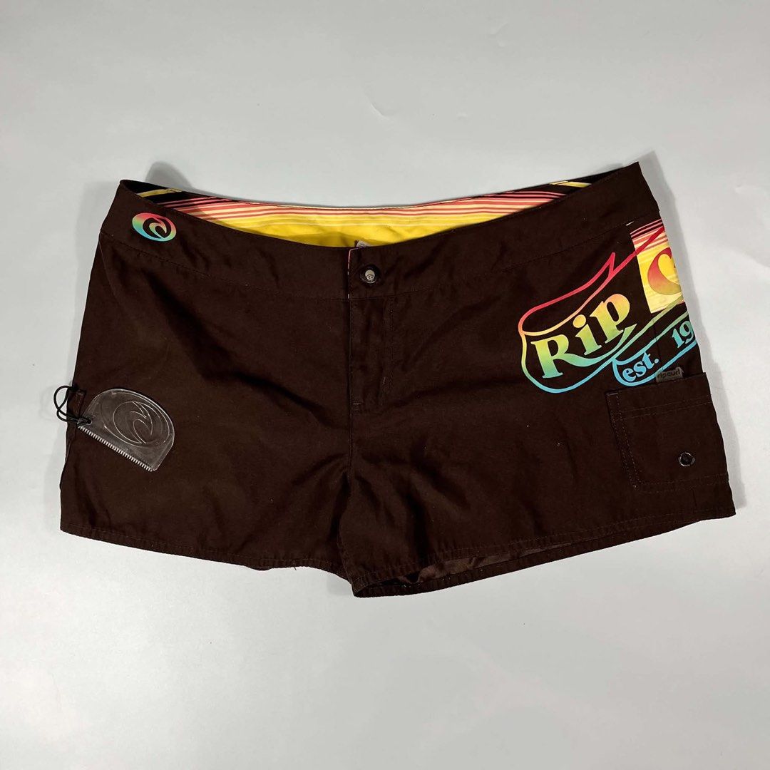 Rip Curl Retro Sun Print Board Shorts Brown (Category: Swim Trunks & Board Shorts) located in Iloilo. Submitted by dripnest.ilo (Listing ID 1471098905, Image 1). Description: - Brand: Rip Curl - Color/Design: Brown with colorful retro stripes and sun graphics - Special Feature: Side cargo pocket with attached wax comb - Details: Vibrant rainbow fading on logo and back panel, yellow-lined waistband - Closure: Button fly - Style: Classic surf aesth