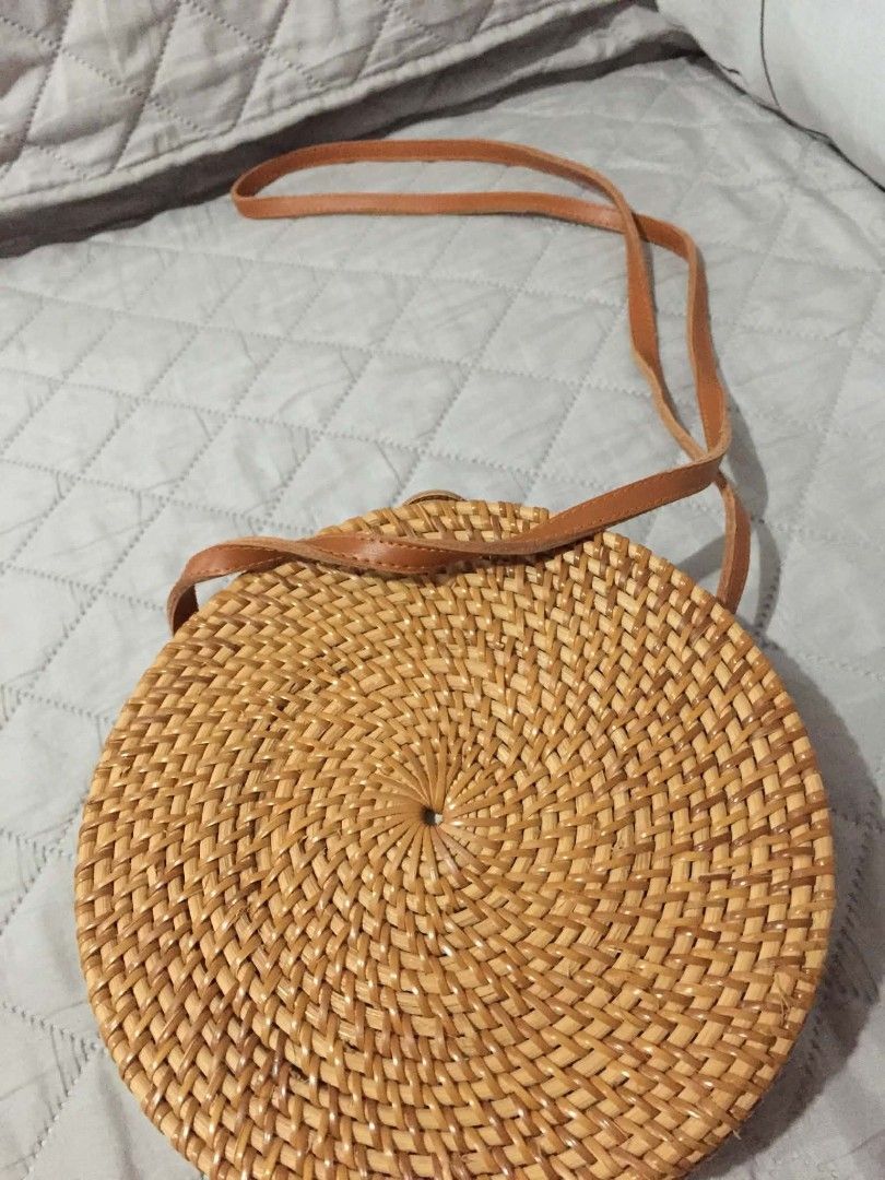 Round Rattan Crossbody Bag with Batik Lining (Category: Cross-body Bags) located in Muntinlupa City. Submitted by prelovedbyanney (Listing ID 1471090554, Image 3). Description: - Style: Round structured rattan straw bag - Closure: Secure snap button with brown leather strap - Interior: Lined with colorful batik fabric - Wear: Long strap suitable for shoulder or crossbody wear - Texture: Natural woven design throughout.