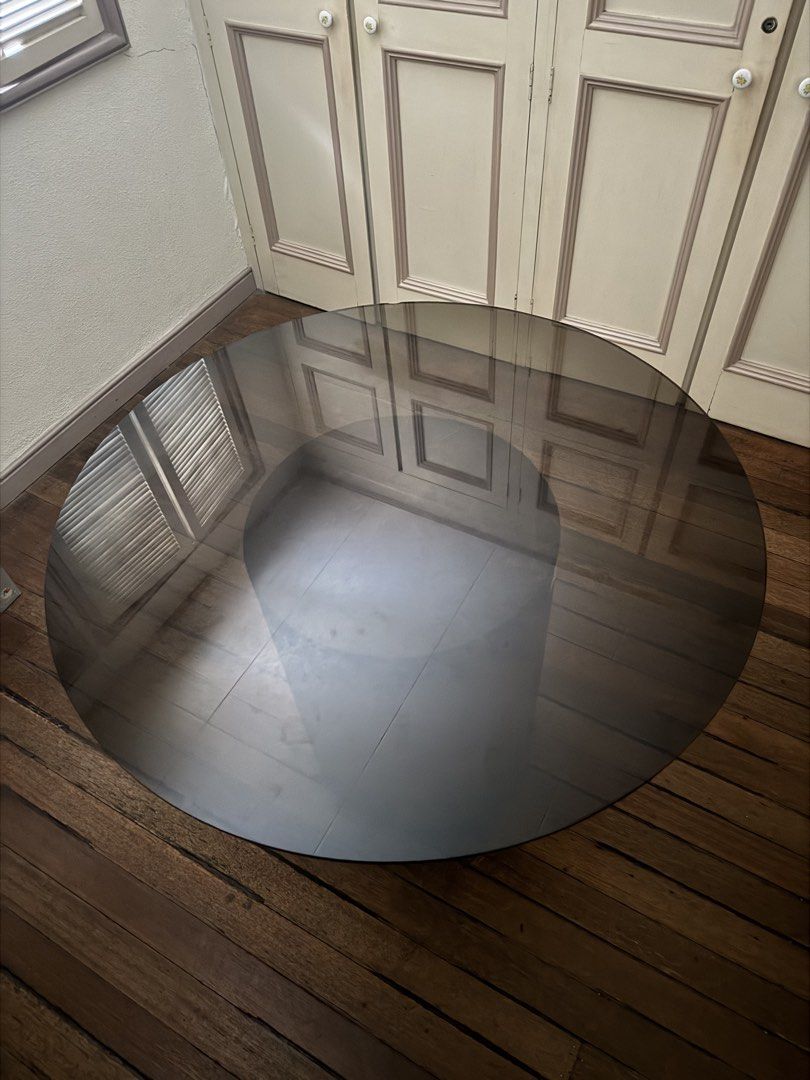 Round Smoke Glass Dining Table with Fluted Wood Base (Category: Tables & Sets) located in Makati City. Submitted by maria.1024 (Listing ID 1471117463, Image 2). Description: Modern round dining table with a smoked-glass tabletop and an elegant cylindrical pedestal base featuring vertical fluted detailing in a bronze-brown finish. Dimensions: * Glass tabletop diameter: 42 inches * Pedestal base diameter: 19 inches * Overall height: 28 inches Condi
