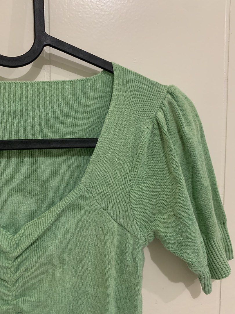 Sage Green Knit Puff Sleeve Ruched Top (Category: Blouses) located in Pasig City. Submitted by lovedbyri (Listing ID 1470953324, Image 2). Description: - Color: Sage green - Style: Fitted knit top with short puff sleeves and square neckline - Details: Ruched front with ribbed texture on collar, cuffs, and hem - Material: Stretchy, super comfortable fabric - Versatility: Great for casual days or paired with high-waisted jeans.