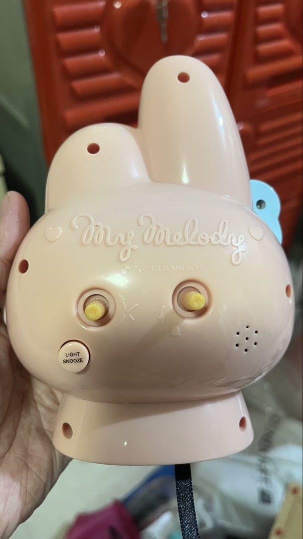 Sanrio My Melody Pink Alarm Clock (Category: Clocks) located in Bay. Submitted by ronellie (Listing ID 1471091741, Image 2). Description: - Authentic Sanrio My Melody desk alarm clock in a charming light pink color - Features an adorable blue bow on the ear and a flower accent at the base - Classic analog clock face with clear numbers for easy reading - Back includes adjustment knobs and a convenient light/snooze button - Stamped official copyrig