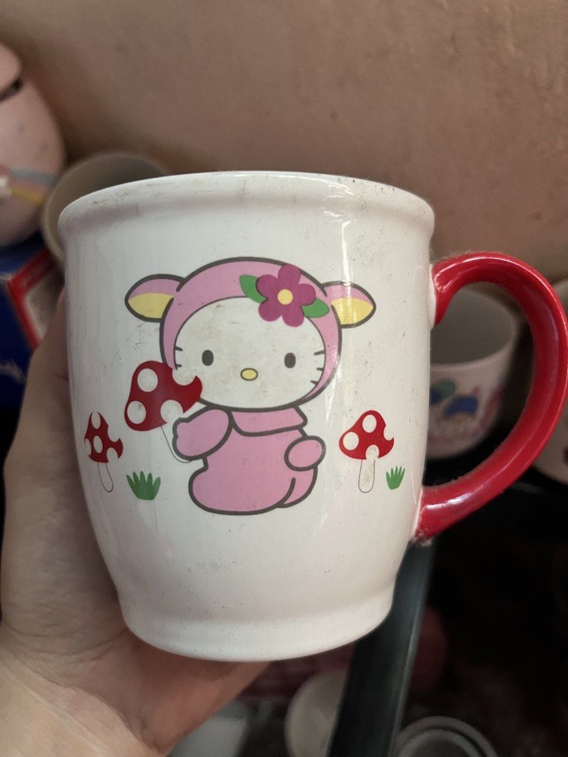 Sanrio Vivitix Hello Kitty Mushroom Ceramic Mug (Category: Coffee & Tea Tableware) located in Manila. Submitted by janetecson05 (Listing ID 1471118166, Image 1). Description: - Authentic Sanrio Vivitix Kitty ceramic mug (Dated 1976, 2000 Sanrio Co., Ltd.) - Features Kitty in a pink outfit surrounded by cute mushrooms and grass - Eye-catching bright red handle and standard mug size - Storage find with minor dust/spots, just needs a quick wash befo