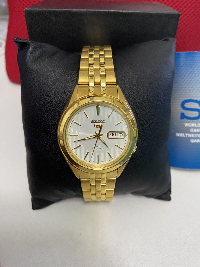 Seiko 5 Automatic Gold Watch with White Dial (Category: Men's Watches) located in Baguio. Submitted by masterroller (Listing ID 1470970577, Image 1). Description: - Brand: Seiko 5 Automatic Watch - Color/Finish: Gold tone casing and matching metal bracelet with folding clasp - Dial: White textured dial with day and date window at 3 o'clock - Movement: 21 jewels automatic movement with exhibition case back - Condition: Minimal wear on casing and b