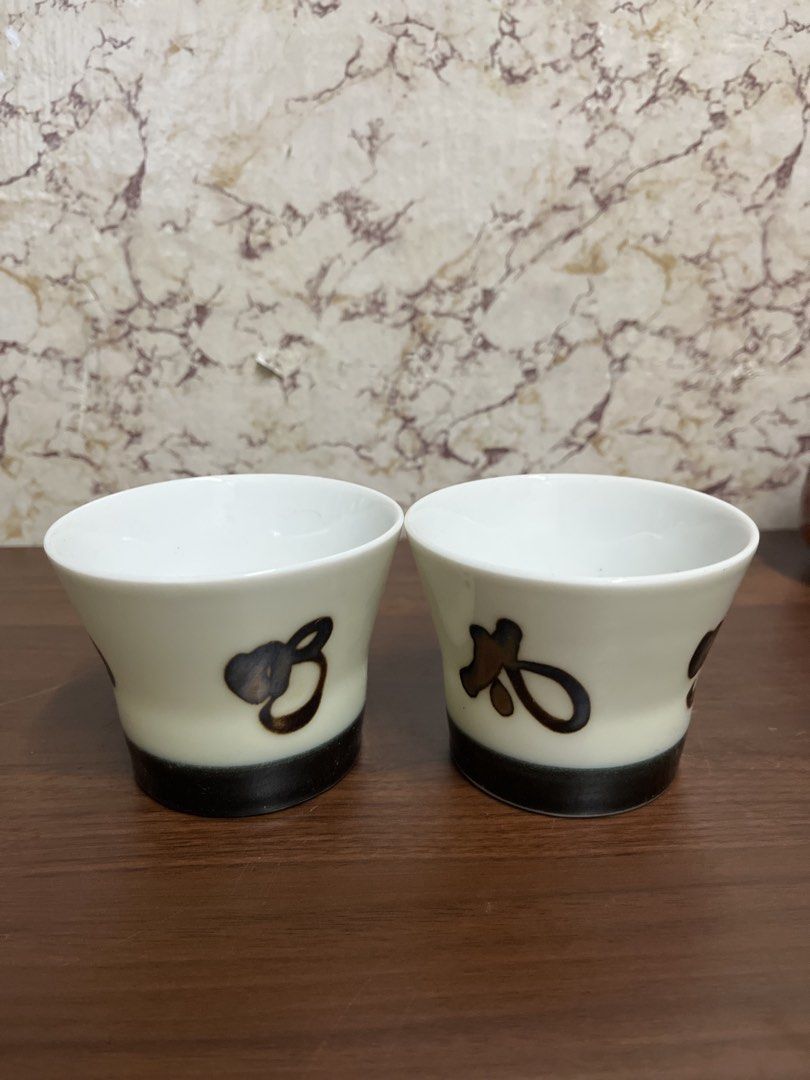 Set of two ceramic tea cups with brushstroke design (Category: Coffee & Tea Tableware) located in Manila. Submitted by kayerrr.gem (Listing ID 1471046788, Image 1). Description: - Set of 2 matching ceramic cups - Cream bodies with unique dark brushstroke designs - Contrasting black bottom band and clean white interior - Durable heavy glaze finish - Perfect for tea, sake, or cold drinks.