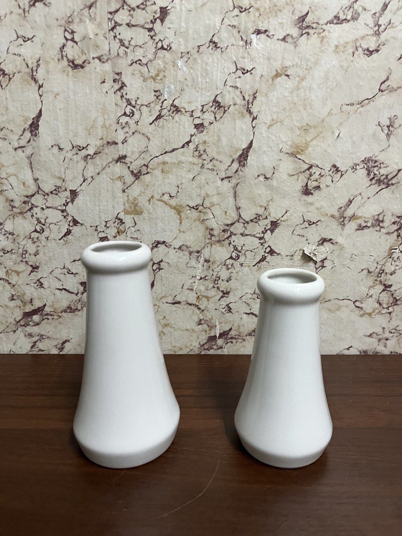 Set of two white ceramic bud vases (Category: Vases & Decorative Bowls) located in Manila. Submitted by kayerrr.gem (Listing ID 1471046929, Image 2). Description: - Set of 2 white ceramic vases in varying heights - Minimalist modern style with flared bases and rounded rims - Smooth, glossy glaze finish - Ideal for single stems or small floral arrangements - Neutral tone complements any home decor - Condition: Bottoms show minor wear and discolora