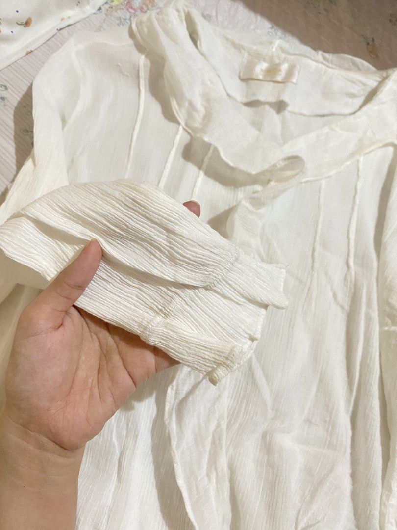 Simida White Ruffle Collar Button-Down Blouse (Category: Blouses) located in Imus. Submitted by softclosetph (Listing ID 1471108473, Image 2). Description: - Brand: Simida - Color: White - Style: Long sleeves, button-front closure - Details: Soft ruffle collar, textured crinkle fabric - Fit/Material: Lightweight, easy to pair with skirts or pants - Condition: Clean and well-maintained.