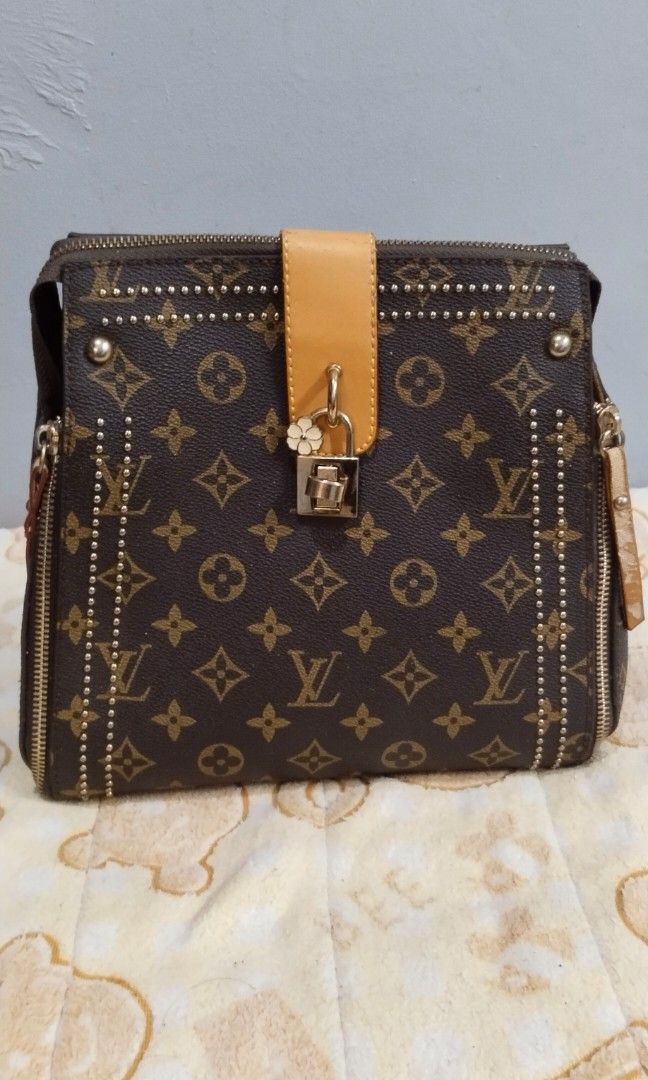 Sling bag (Category: Cross-body Bags) located in Trece Martires City. Submitted by vherma (Listing ID 1470963529, Image 2). Description: shoulder or crossbody handbag featuring a brown Monogram canvas exterior, studded/riveted detailing along the seams and vertical lines, a central tan leather tab, and a turn-lock or padlock closure with a flower accent..