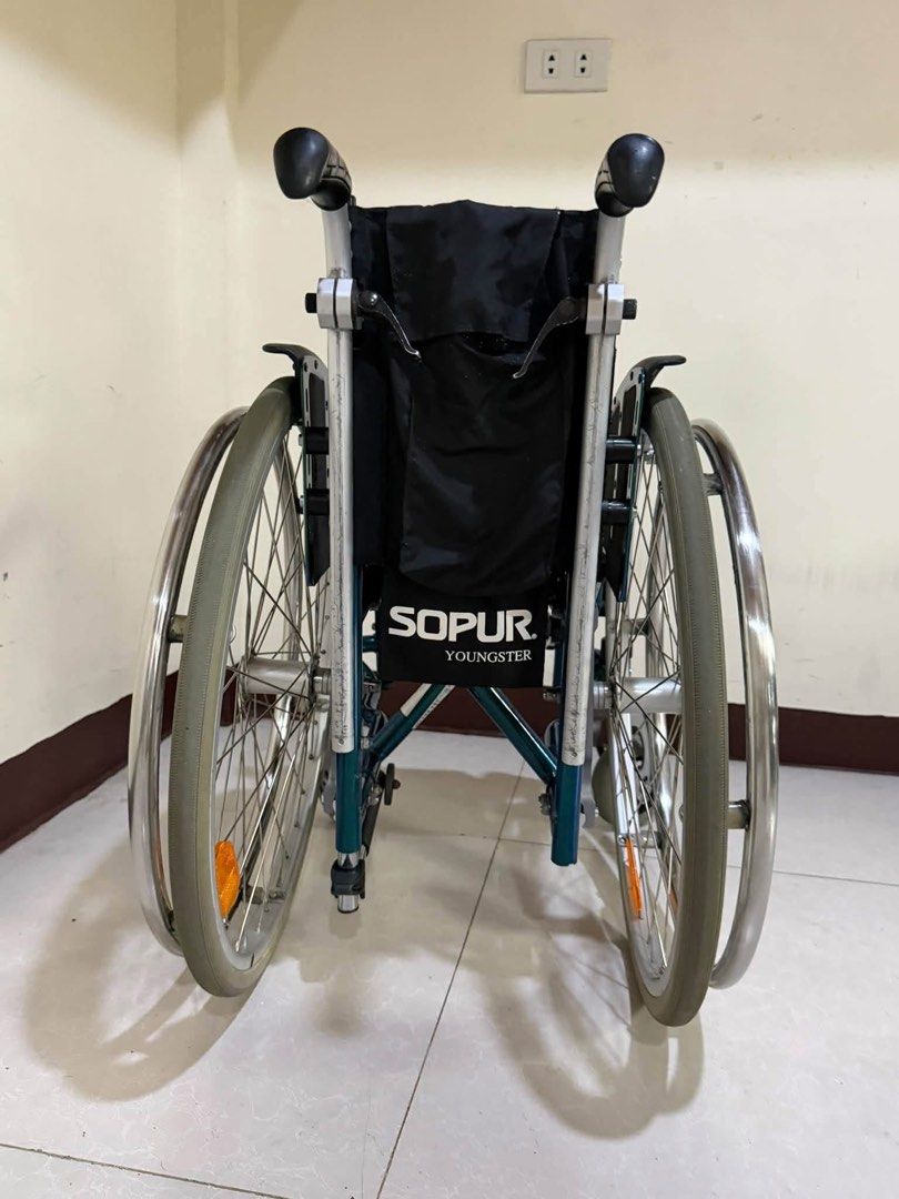 Sopur Youngster Wheelchair (Category: Wheelchairs) located in Manila. Submitted by calmdolphin.87b0e4 (Listing ID 1470957680, Image 1). Description: - Brand/Model: Sopur Youngster wheelchair - Color: Vibrant green and silver frame with black fabric seat and backrest - Portability: Foldable frame design for effortless transport and storage - Storage: Includes a handy storage bag attached to the back - Mobility & Safety: Manual push rims on large r