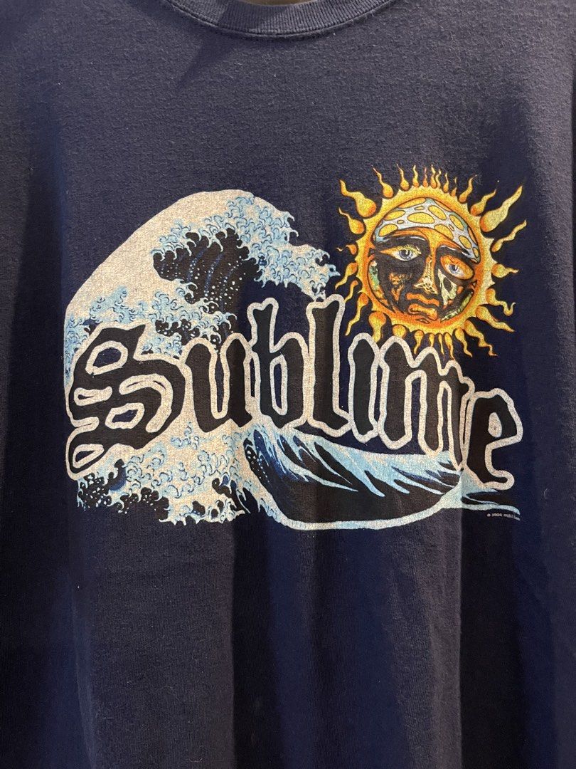 Sublime Band T-Shirt Dark Blue (Category: Tshirts & Polo Shirts ) located in San Fernando. Submitted by bondocmac42825 (Listing ID 1470964586, Image 2). Description: - Brand/Tag: Gildan Heavy Cotton - Color: Dark Navy Blue - Design: Sublime classic sun logo mixed with Japanese great wave graphic - Measurements: 21" pit-to-pit, 29" length - Condition: Small hole near the underarm seam as pictured - Style: Vintage-look band tee, perfect for everyda