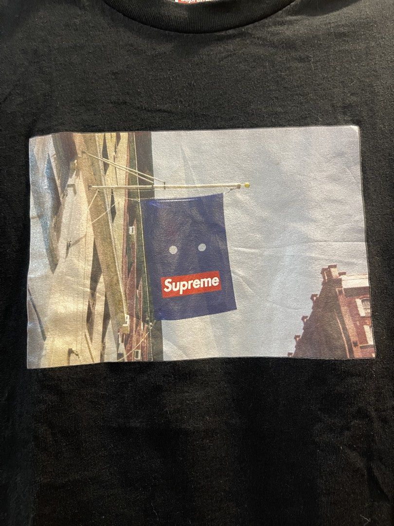 Supreme Flag Black Tee Size S (Category: Tshirts & Polo Shirts ) located in San Fernando. Submitted by bondocmac42825 (Listing ID 1470964640, Image 2). Description: - Brand: Supreme - Color: Solid black with clean collar - Size: Small (approx. 17" width x 26" length) - Design: Chest graphic featuring a blue flag and red box logo - Material: 100% pre-shrunk cotton (Made in China) - Condition: Excellent, well-maintained - Care: Interior tag with wa