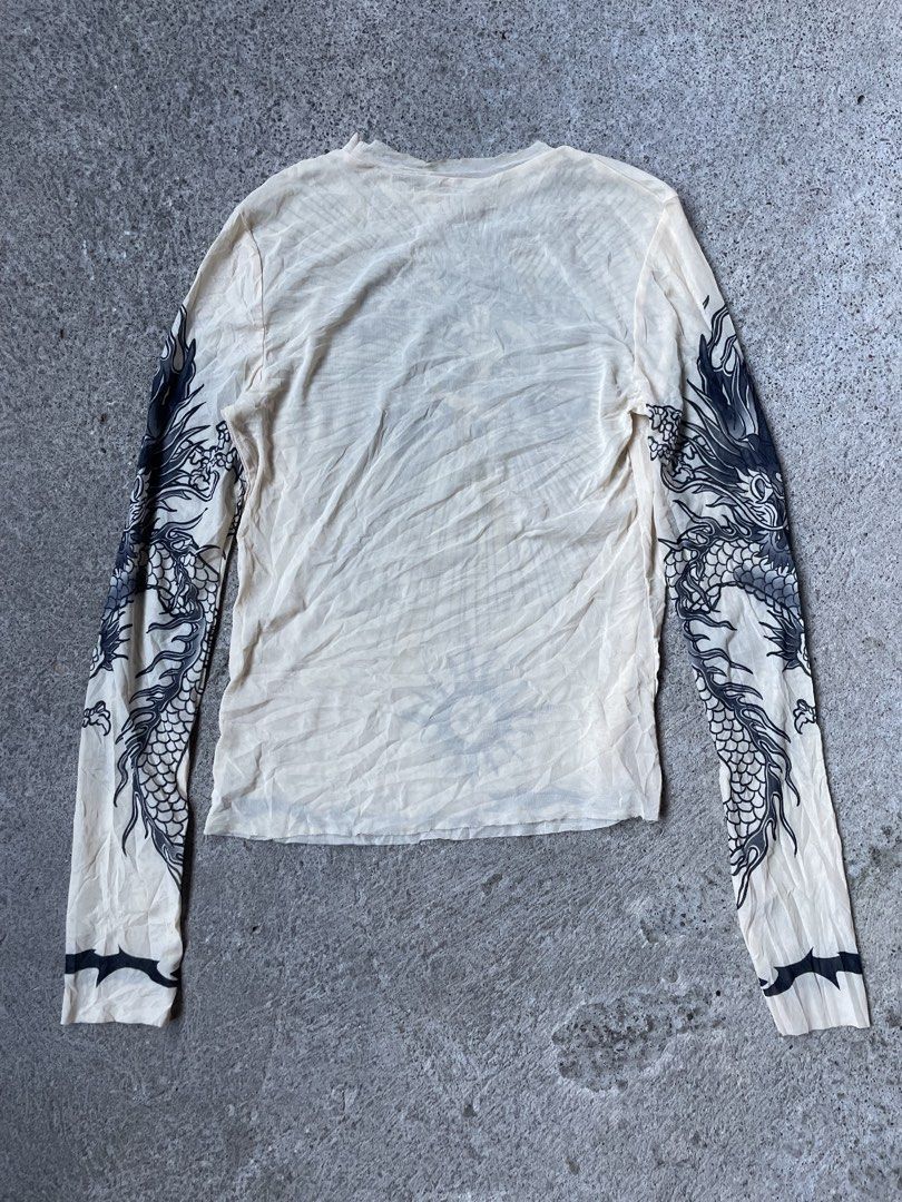 Tattoo Print Long Sleeve Mesh Top Size M (Category: Longsleeves) located in Siniloan. Submitted by rethr1ft (Listing ID 1471016793, Image 2). Description: - 22x15 dimes - Style: Beige long sleeve mesh top with tattoo graphic prints - Details: 'Safe Sex For Ever' chest text, dagger heart motif, sun graphic near hem, and dragon sleeve prints - Size: M (Tag attached) - Material: 95% polyester, 5% elastane.
