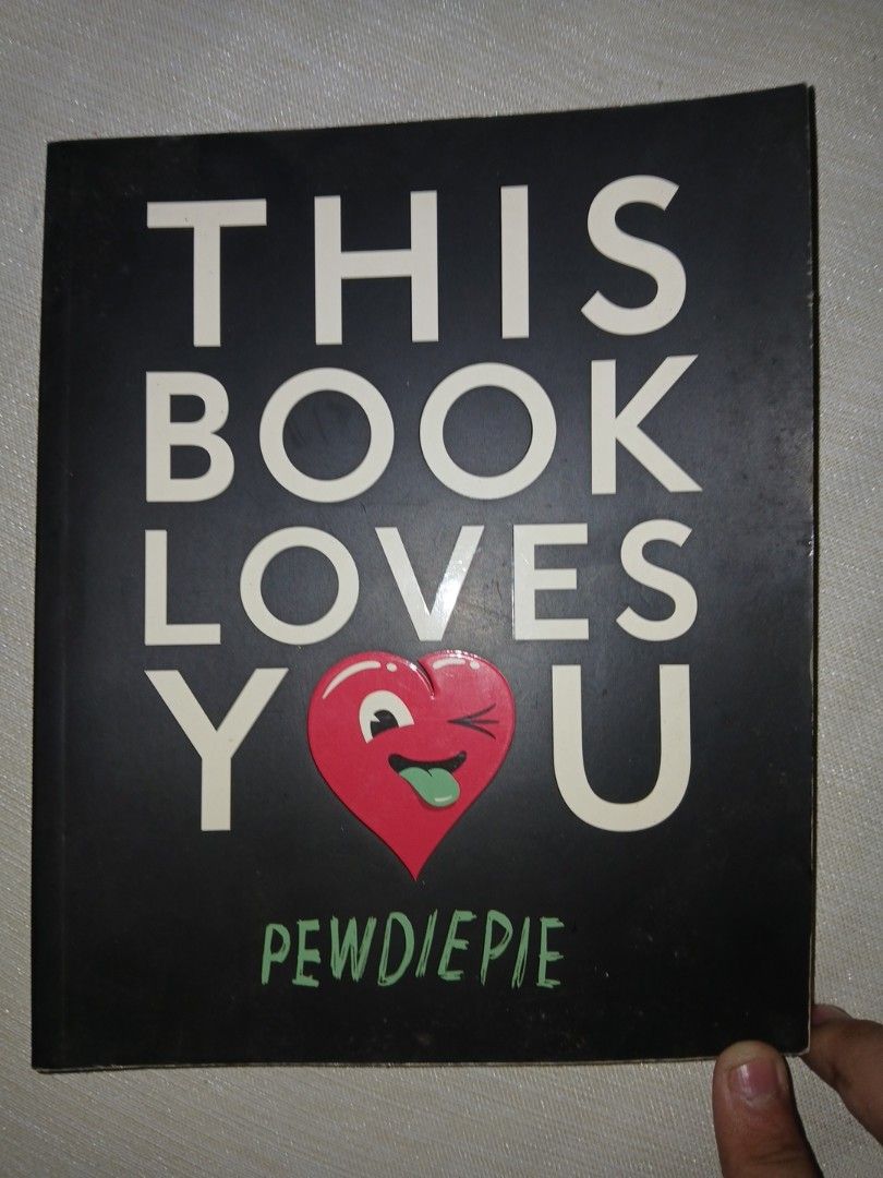 This Book Loves You by PewDiePie (Category: Storybooks) located in Manila. Submitted by bluecurryc30065 (Listing ID 1471031145, Image 1). Description: - Title: This Book Loves You by PewDiePie - Format: Hardcover, standard size - Design: Black cover with white typography and cute red heart graphic - Condition: Minor edge wear from reading and shelf storage - Perfect for: Fans and collectors of Pewdiepie.