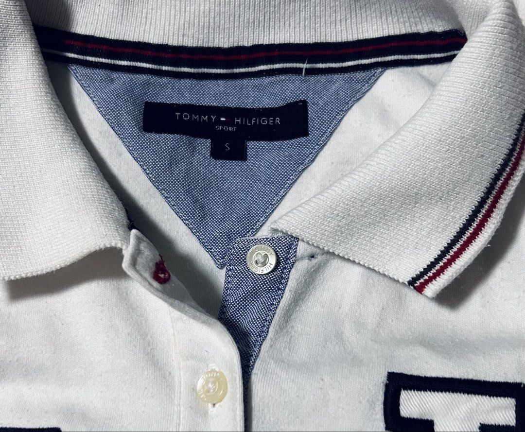 TOMMY HILFIGER (Category: Shirts) located in Davao. Submitted by sart0ria85 (Listing ID 1471081553, Image 3). Description: Comfortable cotton blend. Classic collar with red, white, and blue stripe tipping. Embroidered logo patch on right chest, large 'H' applique on left, and small flag logo near hem. 60%COTTON 40%POLYESTER MADE IN CHINA 🇨🇳 SMALL. Size 4 VERY GOOD CONDITION (84/100) .