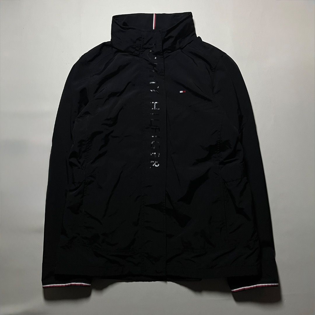 Tommy Hilfiger Black Windbreaker Jacket Size M (Category: Coats, Jackets and Outerwear) located in Caloocan City. Submitted by achilles_grails (Listing ID 1471056915, Image 1). Description: - Brand: Tommy Hilfiger - Style: Windbreaker jacket with full zip and snap button placket - Size: M - Color: Black with iconic red, white, and blue collar details - Design: Bold vertical logo lettering and embroidered chest flag - Material: Lightweight 100% ny
