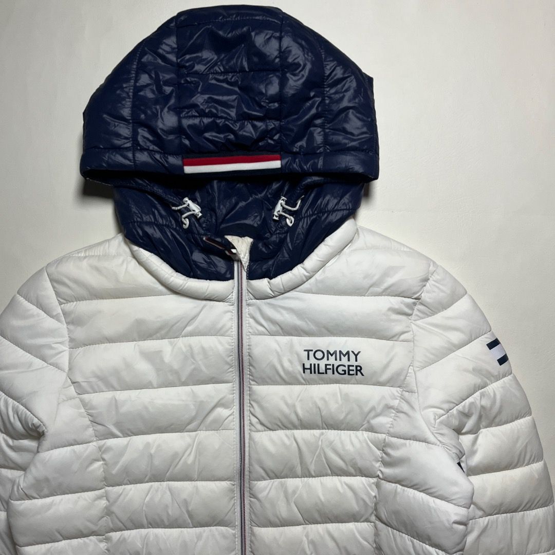 Tommy Hilfiger White Puffer Jacket With Navy Hood (Category: Coats, Jackets and Outerwear) located in Caloocan City. Submitted by achilles_grails (Listing ID 1471055039, Image 2). Description: - Authentic Tommy Hilfiger puffer jacket in crisp white with a contrasting dark blue hood - Full zip-up front closure with practical zipped side pockets - Iconic logo branding on the chest and left sleeve - Material: 100% nylon shell with 100% polyester fil