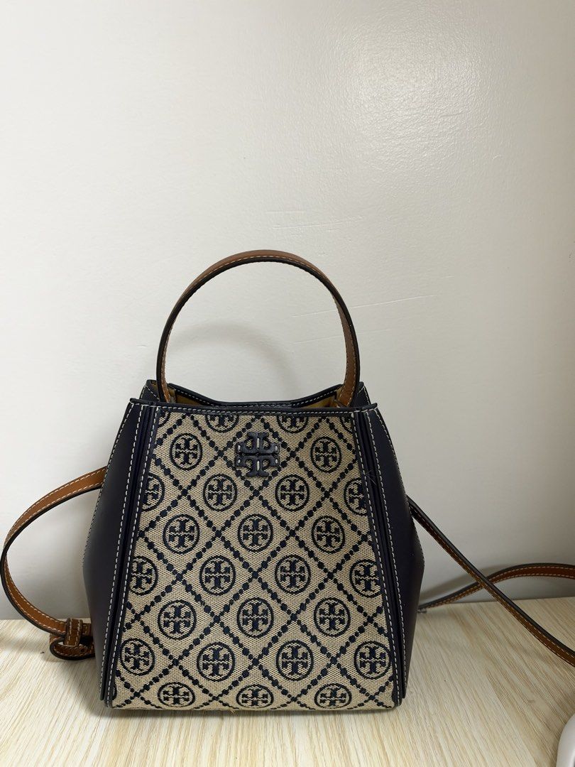 Tory Burch Monogram Jacquard Small Bucket Bag (Category: Luxury Bags & Wallets) located in Manila. Submitted by cat-d526 (Listing ID 1470984098, Image 3). Description: - Brand: Tory Burch - Design: Navy and cream diamond monogram canvas with dark navy leather side panels and white contrast stitching - Hardware: Gold-tone - Straps: Brown top handle and adjustable crossbody strap - Closure: Open top with internal magnetic tab strap - Interior: Neut