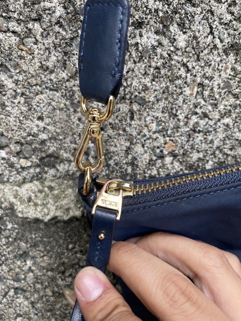 TUMI Navy Blue Nylon Crossbody Bag with Gold Hardware (Category: Cross-body Bags) located in Cebu City. Submitted by lucky.finds.ph (Listing ID 1470972733, Image 3). Description: - Brand: TUMI - Color: Navy blue nylon with gold-tone hardware - Strap: Adjustable blue strap with lobster clasps on both ends - Interior: Light beige fabric lining with pockets and TUMI brand patch - Condition: Clean exterior and interior - Size: Compact, ideal for dail