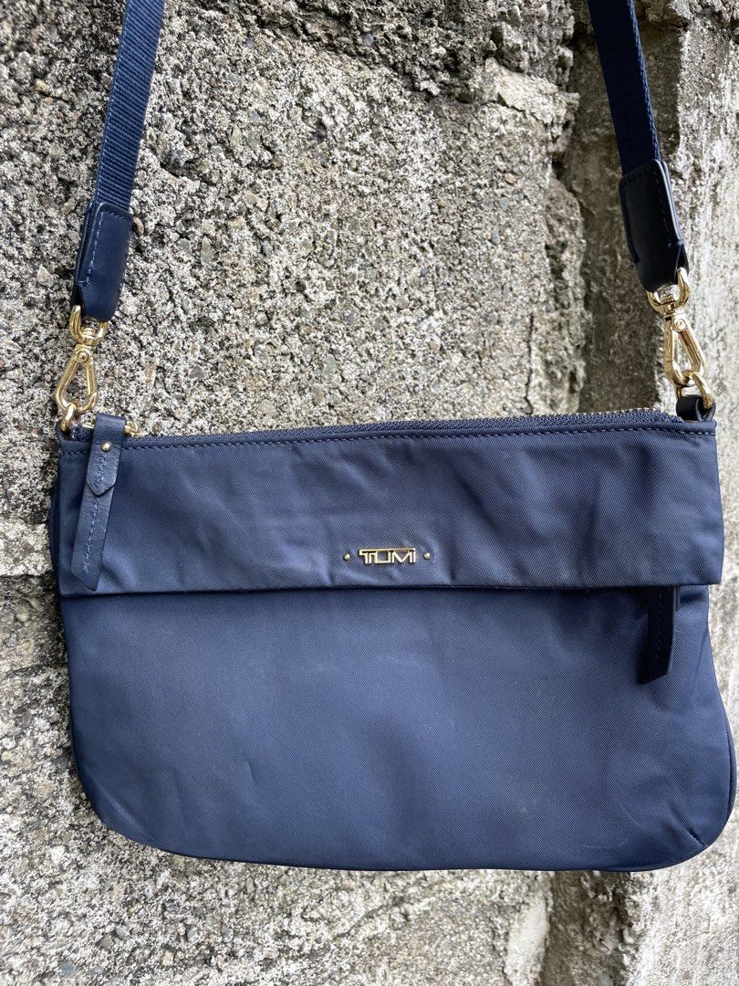 TUMI Navy Blue Nylon Crossbody Bag with Gold Hardware (Category: Cross-body Bags) located in Cebu City. Submitted by lucky.finds.ph (Listing ID 1470972733, Image 2). Description: - Brand: TUMI - Color: Navy blue nylon with gold-tone hardware - Strap: Adjustable blue strap with lobster clasps on both ends - Interior: Light beige fabric lining with pockets and TUMI brand patch - Condition: Clean exterior and interior - Size: Compact, ideal for dail