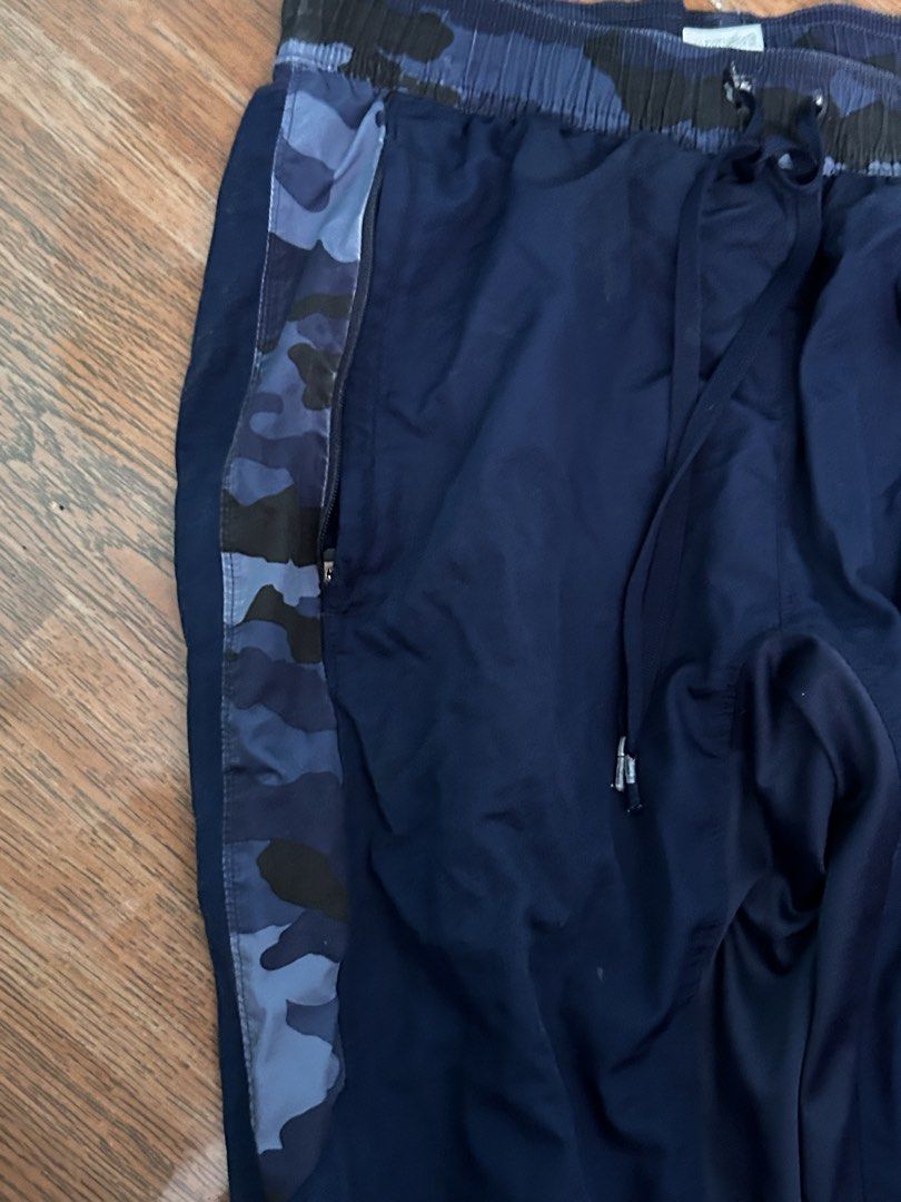 Under Armour Blue Camo Track Pants (Category: Joggers) located in Manila. Submitted by lovely.453 (Listing ID 1470960189, Image 3). Description: - Brand: Under Armour size 26-30 adjustable waist - Color: Navy blue with blue camo waistband and side panels - Material: 100% polyester (lightweight and breathable) - Waist: Elastic with drawstring closure - Pockets: Secure zippered pockets on both sides - Origin: Made in Vietnam - Condition: Excellent 
