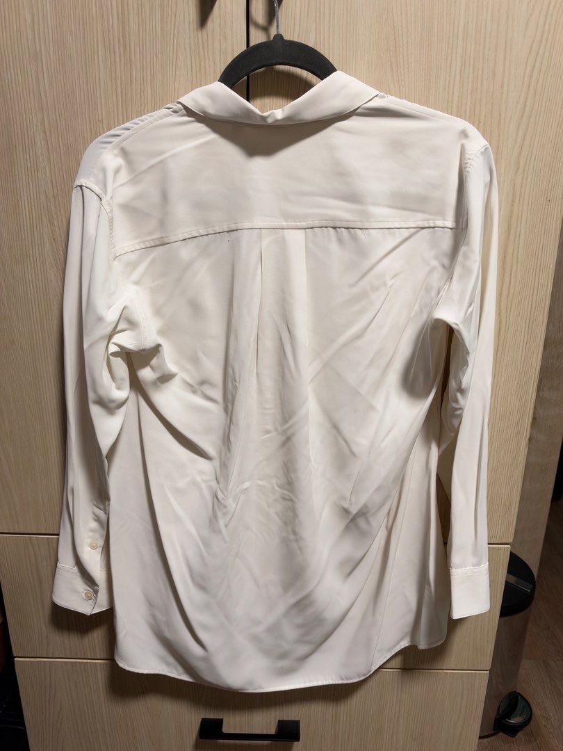 Uniqlo White Long Sleeve Button-Up Blouse (Category: Longsleeves) located in Makati City. Submitted by rmgcloset (Listing ID 1471115526, Image 3). Description: - Brand: Uniqlo - Color: Off-white - Size: Small - Style: Long sleeve button-up with classic collar - Details: Two front flap pockets, button cuffs, and slightly curved back hem - Fabric: Lightweight with a smooth finish - Condition: Excellent, clean look - Perfect for: Workwear, smart-cas