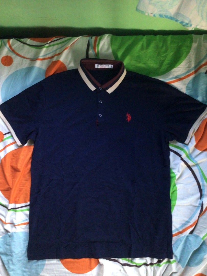 USPA Polo Shirt (Category: Tshirts & Polo Shirts ) located in General Trias. Submitted by dunht (Listing ID 1471082342, Image 1). Description: - Brand: U.S. Polo Assn. - Color: Navy blue with beige and maroon contrast collar and sleeve trim - Size: 2XL (based on inner neck tag) - Design: Short sleeve, 3-button placket with blue buttons, and signature red embroidered horse logo on left chest - Condition: Pre-loved, well-maintained - Perfect for: S