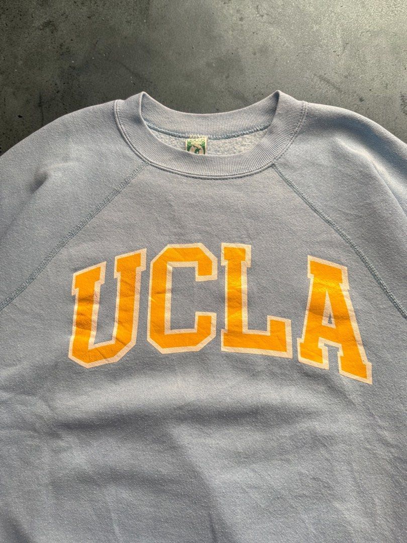 Vintage 1980’s UCLA Sweater (Category: Coats, Jackets and Outerwear) located in Pasig City. Submitted by hoardwrld (Listing ID 1470993459, Image 3). Description: Width: 24 Length: 27.5 - Brand/Style: Vintage Discus Athletic crewneck sweatshirt - Design: UCLA collegiate graphic in yellow with white outline - Color: Light blue heather with raglan sleeves - Details: Ribbed collar, cuffs, hem, and classic green woven tag - Origin: Made in USA - Size:
