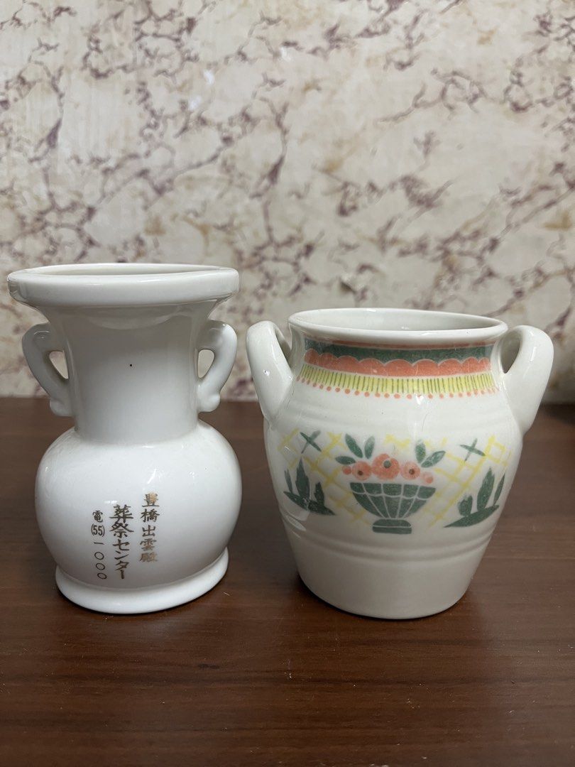 Vintage Ceramic Vases Pair with Handles and Floral Pattern (Category: Vases & Decorative Bowls) located in Manila. Submitted by kayerrr.gem (Listing ID 1471046468, Image 2). Description: - Set of 2 vintage white glazed ceramic vases with double side handles - Vase 1: Features elegant gold Japanese lettering and telephone number print - Vase 2: Decorated with a vibrant basket and flower pattern near the base, plus yellow and orange top rim trim - 