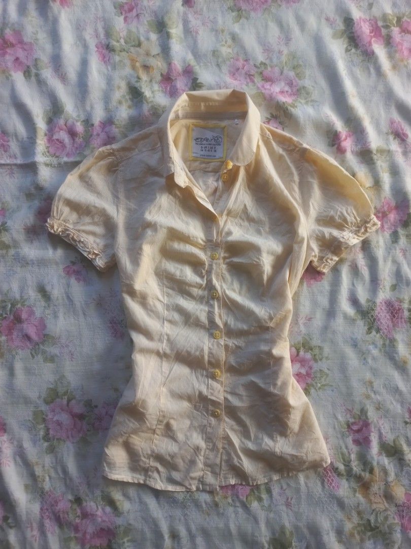 Vintage Esprit Yellow Short Sleeve Button-Down Blouse (Category: Blouses) located in Davao. Submitted by bloodyriz (Listing ID 1470933337, Image 1). Description: - Brand: Vintage Esprit - Color: Soft yellow with subtle vertical pinstripes - Details: Classic pointed collar, front ruching along the placket - Sleeves: Short puff sleeves with playful ruffled cuffs - Material: Lightweight and comfortable - Condition: Great basic for casual wear or sma