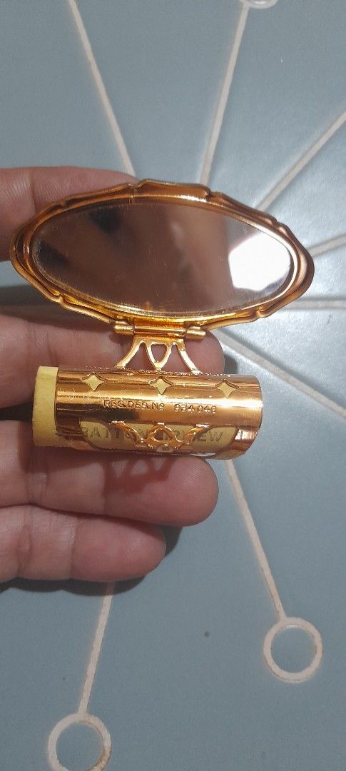 Vintage Gold Lipstick Case with Mirror (Category: Makeup) located in Bocaue. Submitted by marajapansurplus (Listing ID 1470971055, Image 2). Description: - Vintage gold lipstick holder with built-in side mirror - Features a vibrant red rose floral design on textured gold casing - Detailed with diamond cut-outs and intricate engraved markings - Compact and lightweight, fits easily in small purses or handbags - Stunning retro piece for your vanity 