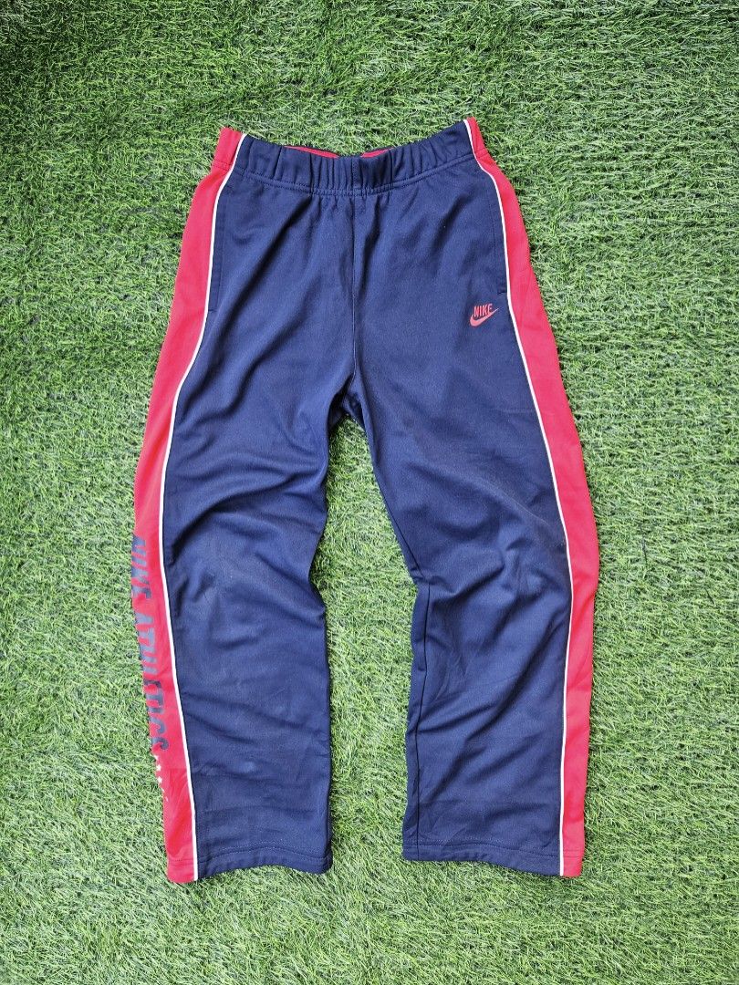 Vintage Nike Track Pants (Category: Joggers) located in Las Pinas. Submitted by rcp123 (Listing ID 1470987208, Image 1). Description: 24 - 28 waistline length 35 legopen 8 issue: minimal gasgas lang un lang - Brand: Nike Athletics - Size: Medium (fits height 140-150cm) - Color: Dark navy blue with red side panels and white piping - Details: Embroidered Nike logo and bold vertical 'NIKE ATHLETICS' leg print with stars - Fit: Comfortable elastic wa