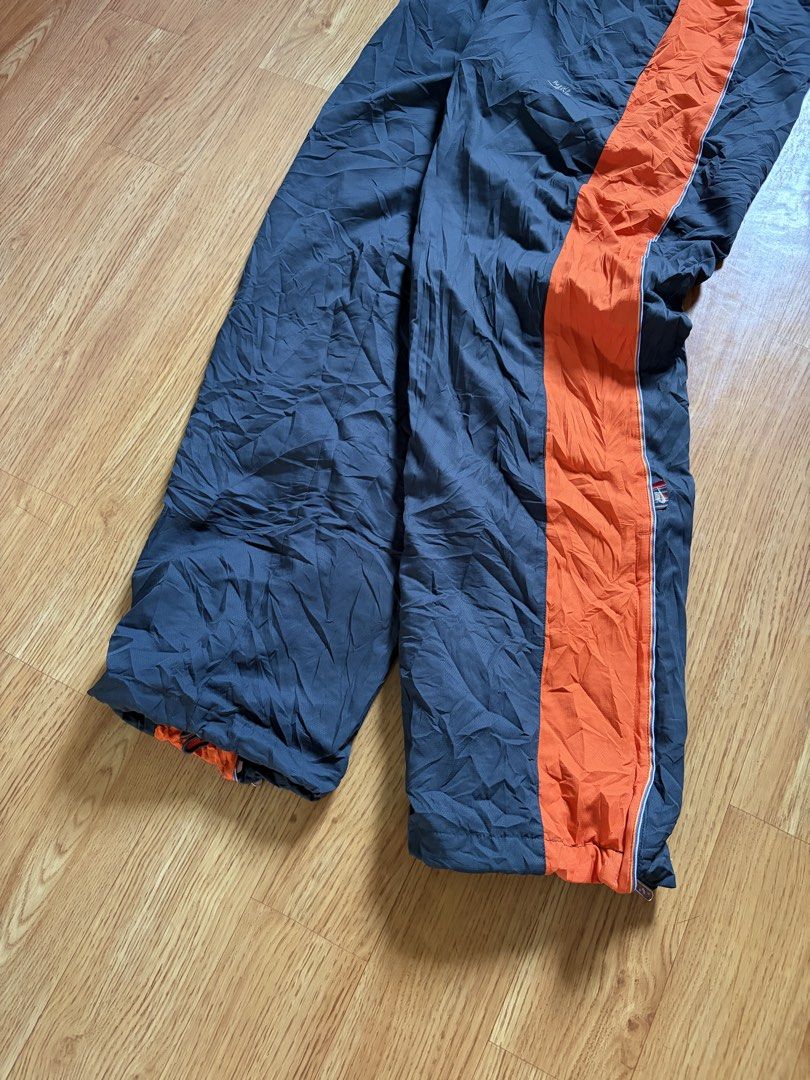 Vintage Nike Track Pants Dark Grey Orange (Category: Joggers) located in Angeles City. Submitted by repurposedwear (Listing ID 1471116163, Image 3). Description: Vintage Nike track pants in dark grey and orange. Size L / US 34. Features lightweight nylon material, a rare rainbow woven tag, adjustable elastic drawstring waist, and bottom side zips with ankle toggle cinch cords. Great vintage condition. Issues : nike logo on the thigh is faded, als