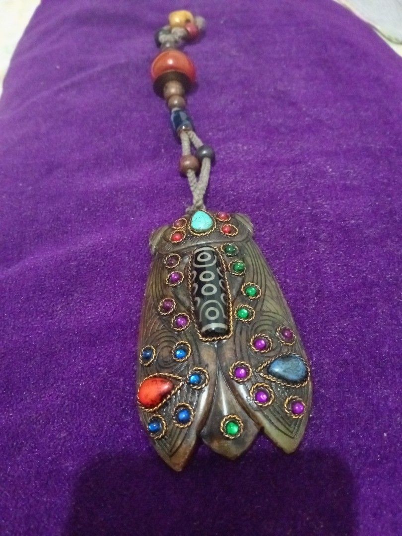 Vintage old jade cicada amulet with dzi agate (Category: Vintage Collectibles) located in Batangas. Submitted by girlmeetspurple (Listing ID 1471055094, Image 3). Description: This is a cicada-shaped pendant, a design deeply rooted in Chinese and Tibetan cultural traditions. The body is typically carved from jade or serpentine stone, inlaid with colorful stones — notably turquoise at the forehead — and features a Nine-Eye Dzi agate bead down the 