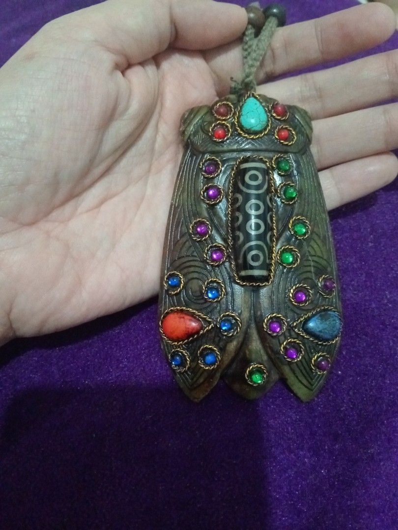 Vintage old jade cicada amulet with dzi agate (Category: Vintage Collectibles) located in Batangas. Submitted by girlmeetspurple (Listing ID 1471055094, Image 1). Description: This is a cicada-shaped pendant, a design deeply rooted in Chinese and Tibetan cultural traditions. The body is typically carved from jade or serpentine stone, inlaid with colorful stones — notably turquoise at the forehead — and features a Nine-Eye Dzi agate bead down the 