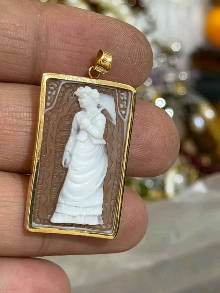 Vintage Rectangular Cameo Pendant With Gold Frame (Category: Necklaces) located in Burgos, Pangasinan. Submitted by mightycat.c7acd6 (Listing ID 1470971458, Image 1). Description: - Design: Carved white Victorian lady holding an umbrella on a brown background - Frame: Shiny yellow gold-toned metal with a decorative patterned border and top bail - Style: Classic, miniature relief carving with a timeless vintage look - Usage: Small, delicate size i