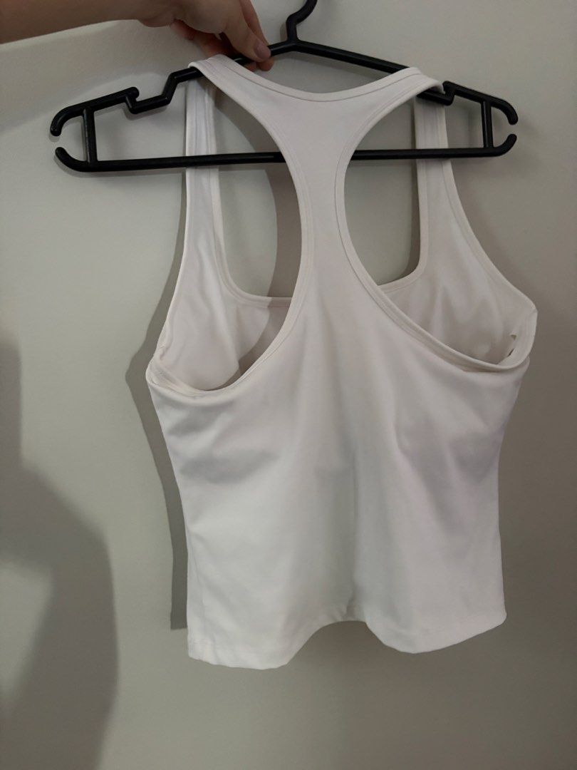 White Racerback Athletic Tank Top (Category: Activewear) located in Manila. Submitted by mika_declutter (Listing ID 1470943900, Image 2). Description: - Color: Solid white - Style: Athletic tank top with trendy square neckline and racerback - Comfort: Soft, stretchy fabric perfect for workouts or casual wear - Extra: Built-in bra lining for added support - Condition: Clean, no stains or marks.