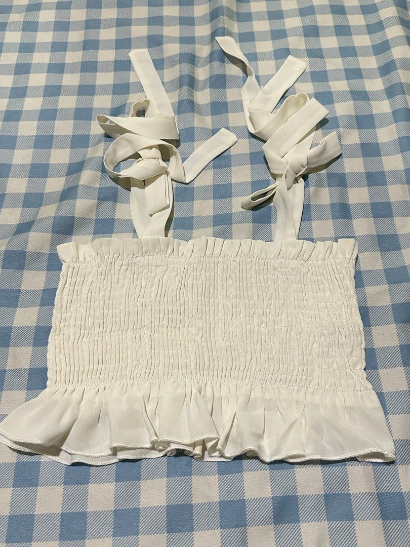 White smocked crop top with tie straps (Category: Sleeveless) located in Mandaluyong City. Submitted by brightbird-5701 (Listing ID 1471062431, Image 1). Description: - Color: White - Style: Smocked crop top with ruffle hem - Straps: Adjustable self-tie shoulder straps - Material: Stretchy fabric for a comfortable fit - Perfect pairing: Looks great with high-waisted jeans or shorts.