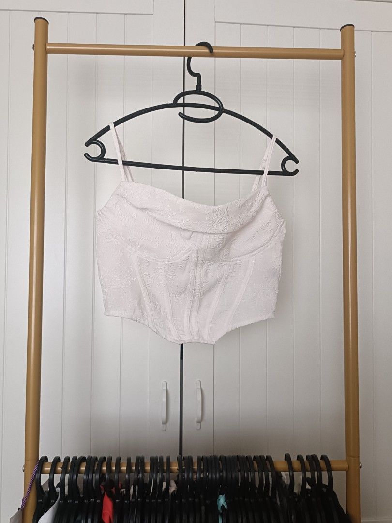 White textured corset crop top (Category: Sleeveless) located in Bacoor. Submitted by Miss_Chuch0521 (Listing ID 1470963290, Image 1). Description: - Color: White with subtle textured floral pattern - Style: Corset-style crop top with structured boning for a fitted shape - Neckline & Straps: Cowl neckline with thin adjustable spaghetti straps - Closure: Exposed silver zipper down the back - Pairing: Looks great with high-waisted denim jeans.